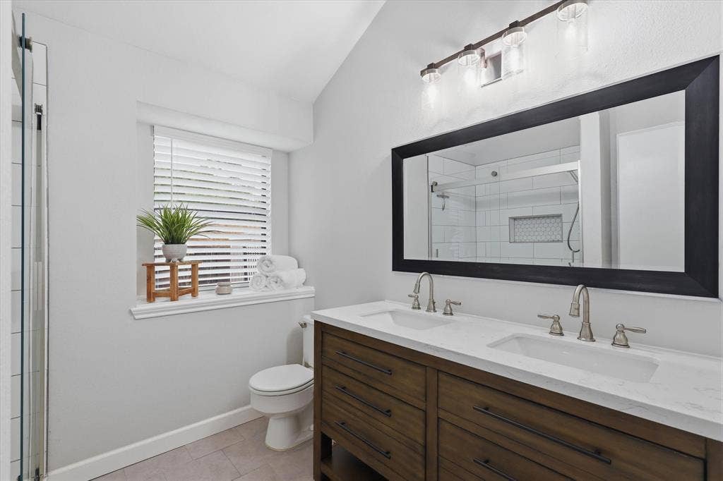 Beautifully updated primary bath features a dual-sink vanity with quartz countertop and an oversized mirror.