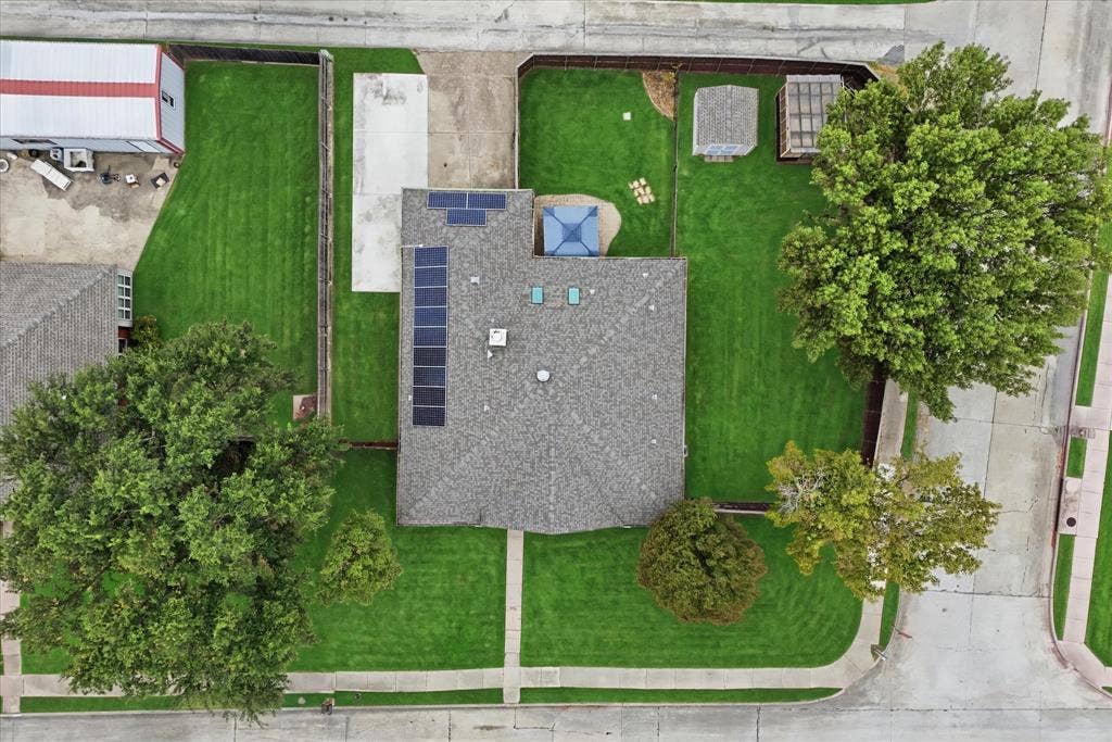 Bird's-eye view highlights the impressive lot size, fenced backyard, covered patio, outbuildings and extended rear parking area.