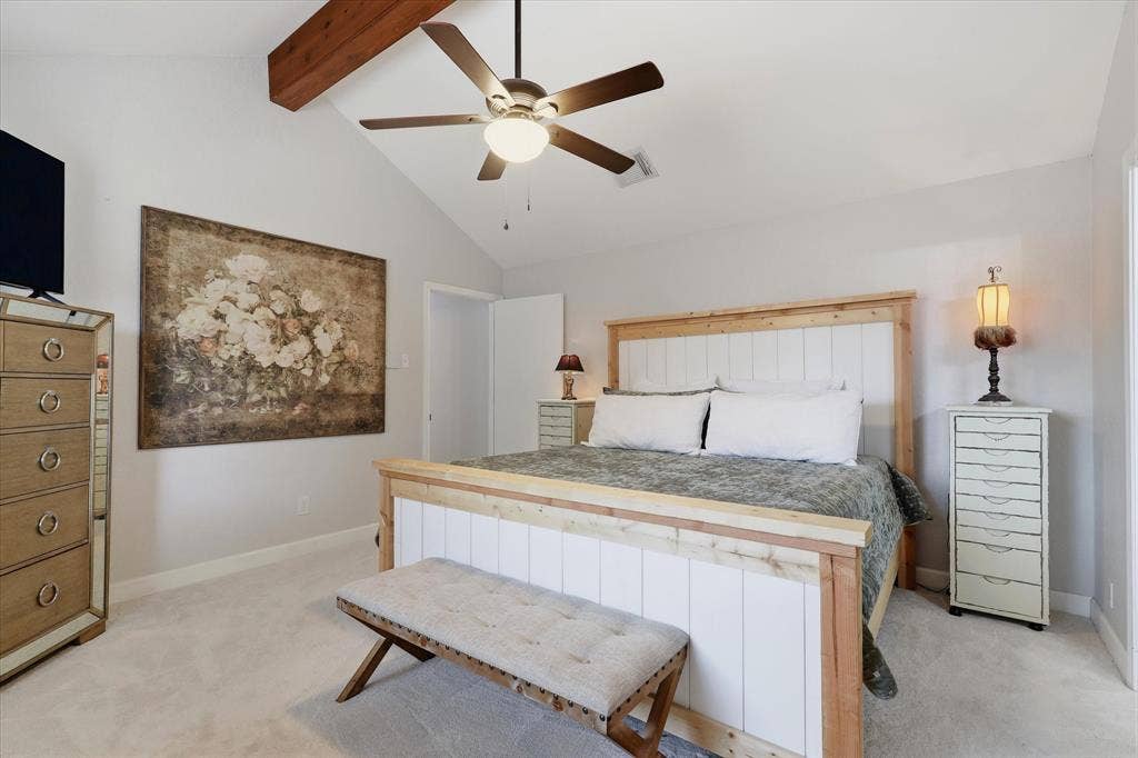 Vaulted ceilings and an exposed wood beam add architectural character to the spacious primary retreat.