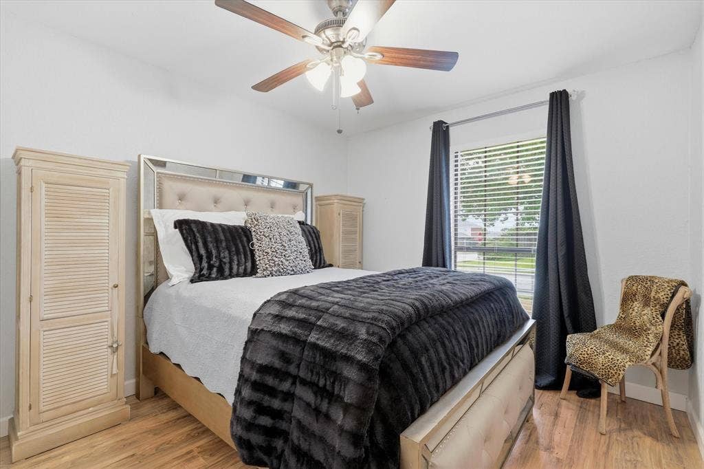 Secondary bedroom with laminate wood flooring, generous natural light and ample space for a queen-size bed.