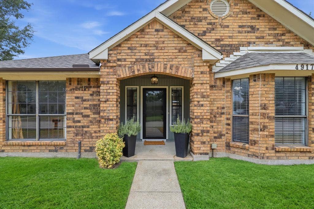 Welcoming covered entry with classic brick detailing and sidelights flanking the front door.