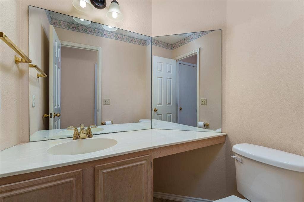 4500 Fargo Drive, Grand Prairie, TX 75052 Bathroom featuring a corner vanity with an integrated sink, dual-paneled mirror, and a brass-finish faucet
