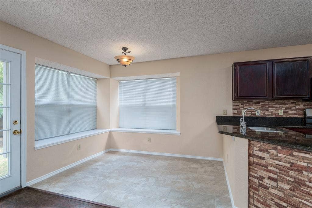 4500 Fargo Drive, Grand Prairie, TX 75052 Tiled flooring, dual windows with blinds, recessed window sills, overhead light fixture, and a built-in breakfast bar with stone-finish siding