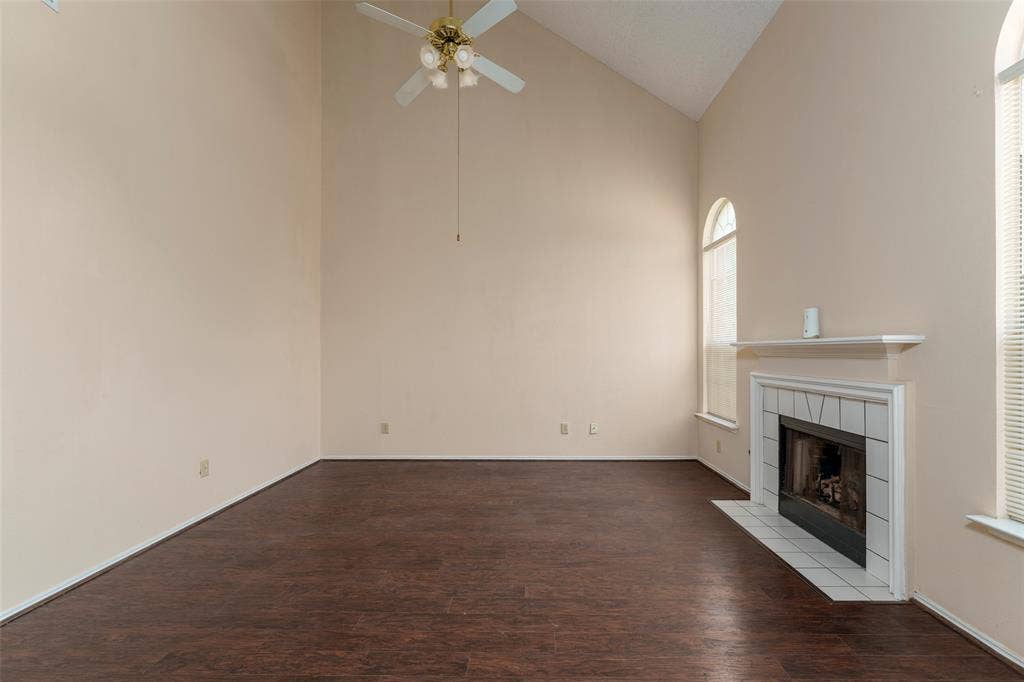 4500 Fargo Drive, Grand Prairie, TX 75052 Vaulted ceiling, wood-finish flooring, fireplace with tile surround and hearth, arched window, and ceiling fan with light fixture