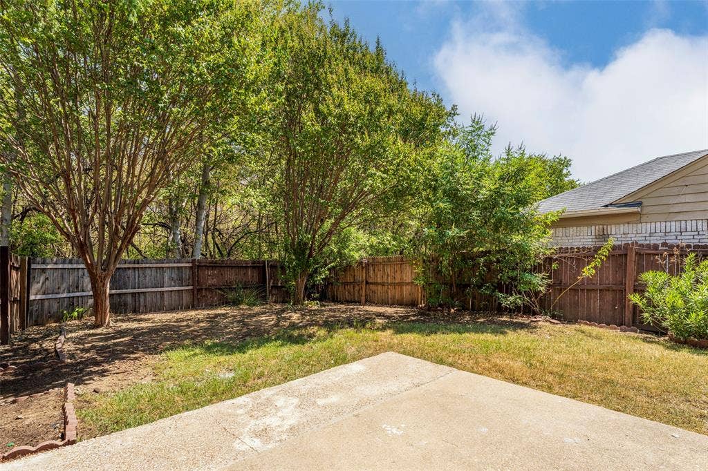 4500 Fargo Drive, Grand Prairie, TX 75052 Rear exterior featuring a concrete patio, wood fencing, and mature trees