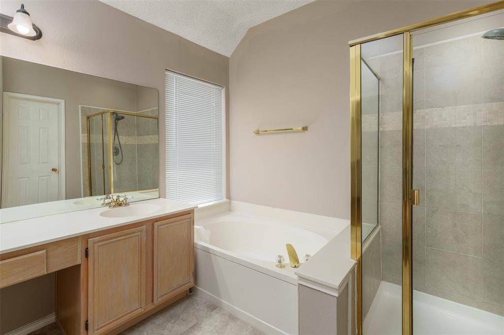 4500 Fargo Drive, Grand Prairie, TX 75052 Vanity with integrated sink, built-in bathtub, and enclosed shower with tile surround
