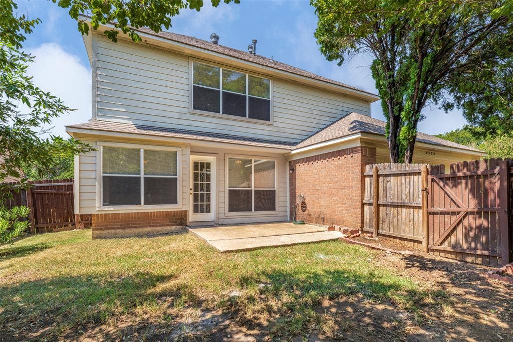 4500 Fargo Drive, Grand Prairie, TX 75052 Back exterior featuring a concrete patio, wood fencing, brick and siding exterior, and a glass-paneled door