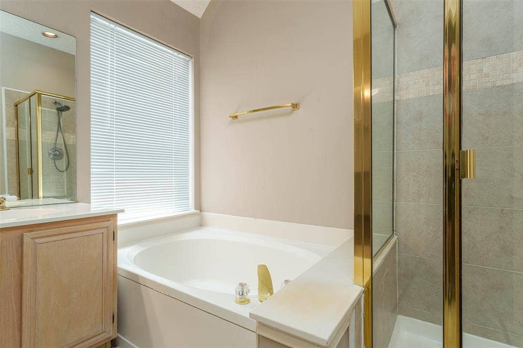 4500 Fargo Drive, Grand Prairie, TX 75052 Built-in soaking tub, a separate glass-enclosed shower, light wood-finish vanity, and a large window with blinds