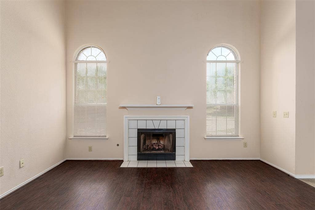 4500 Fargo Drive, Grand Prairie, TX 75052 Vaulted ceiling with dual arched windows, fireplace with white tile surround, and rich wood-finish flooring