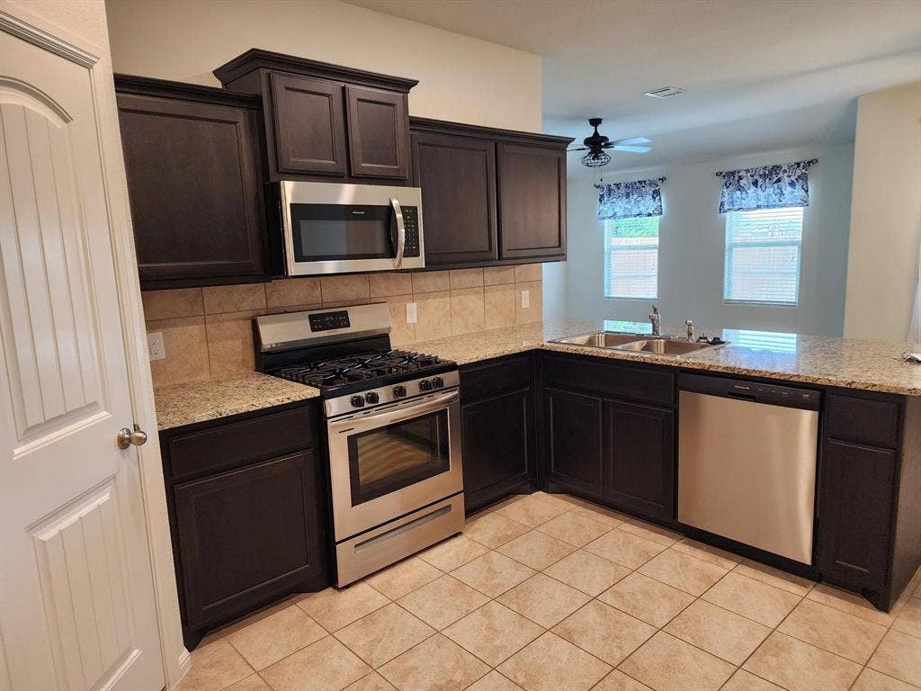 729 Watson Way, Crowley, TX 76036 Kitchen with appliances with stainless steel finishes, backsplash, sink, ceiling fan, and light tile floors