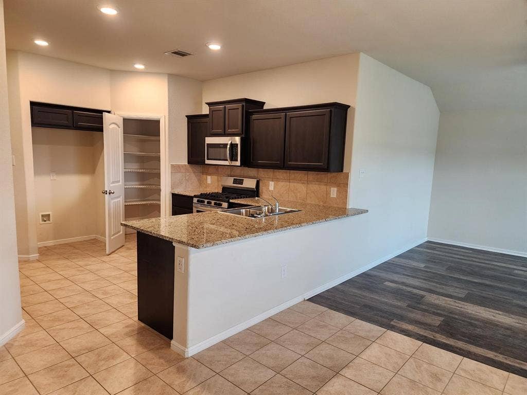729 Watson Way, Crowley, TX 76036 Kitchen with kitchen peninsula, tasteful backsplash, stainless steel appliances, light stone counters, and light tile floors