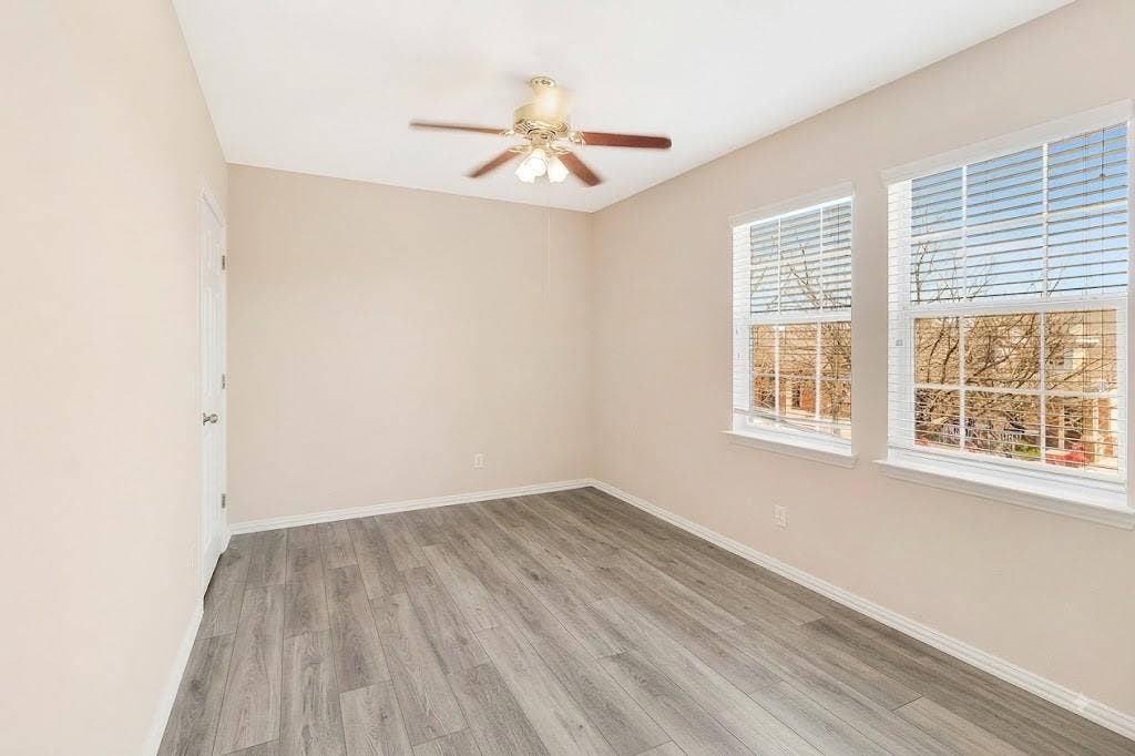 4908 Rushden Road, McKinney, TX 75070 Room featuring wood-finish flooring, two windows with blinds, and a ceiling fan with integrated lighting