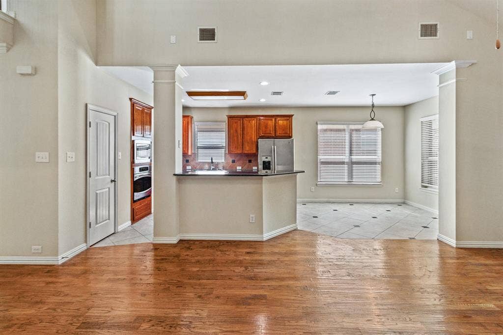 4908 Rushden Road, McKinney, TX 75070 Hardwood flooring, kitchen with wood cabinetry, stainless steel appliances, breakfast bar, and tile flooring
