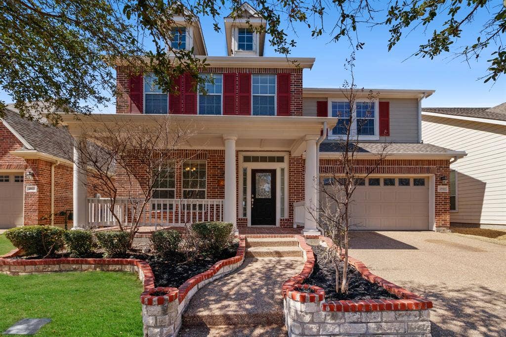 4908 Rushden Road, McKinney, TX 75070 Brick facade with shutters, covered front porch, integrated two-car garage, and a decorative brick and stone planter