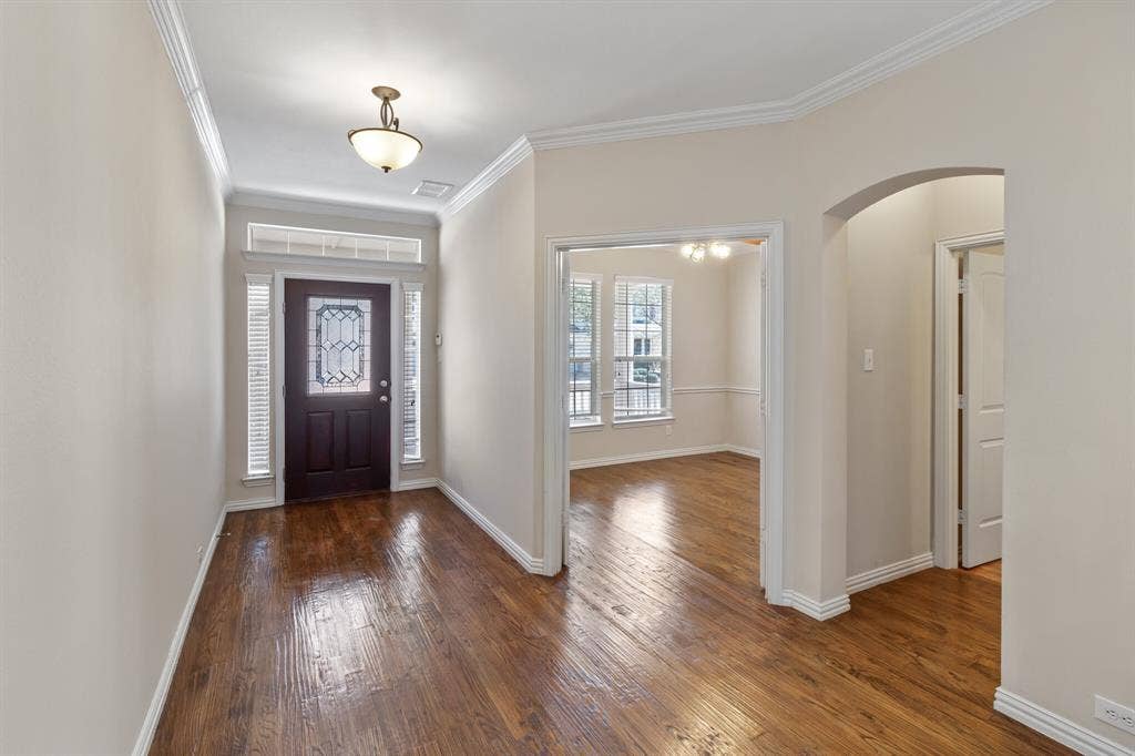 4908 Rushden Road, McKinney, TX 75070 Wood-finish flooring throughout, crown molding detailing, and an arched entry