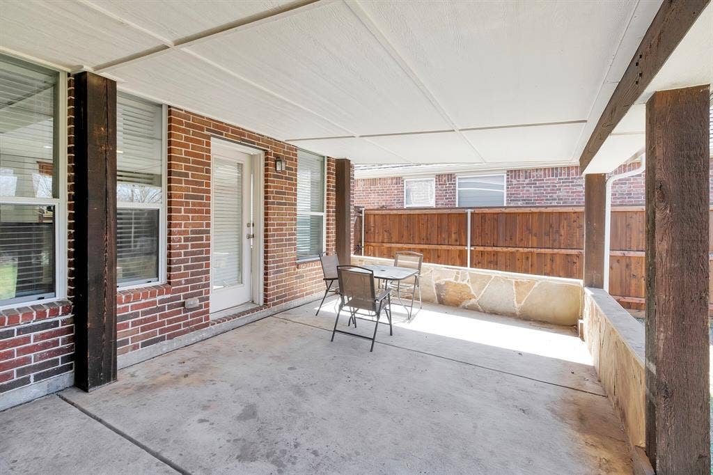 4908 Rushden Road, McKinney, TX 75070 Covered patio featuring concrete flooring, wood support columns, and a brick exterior wall