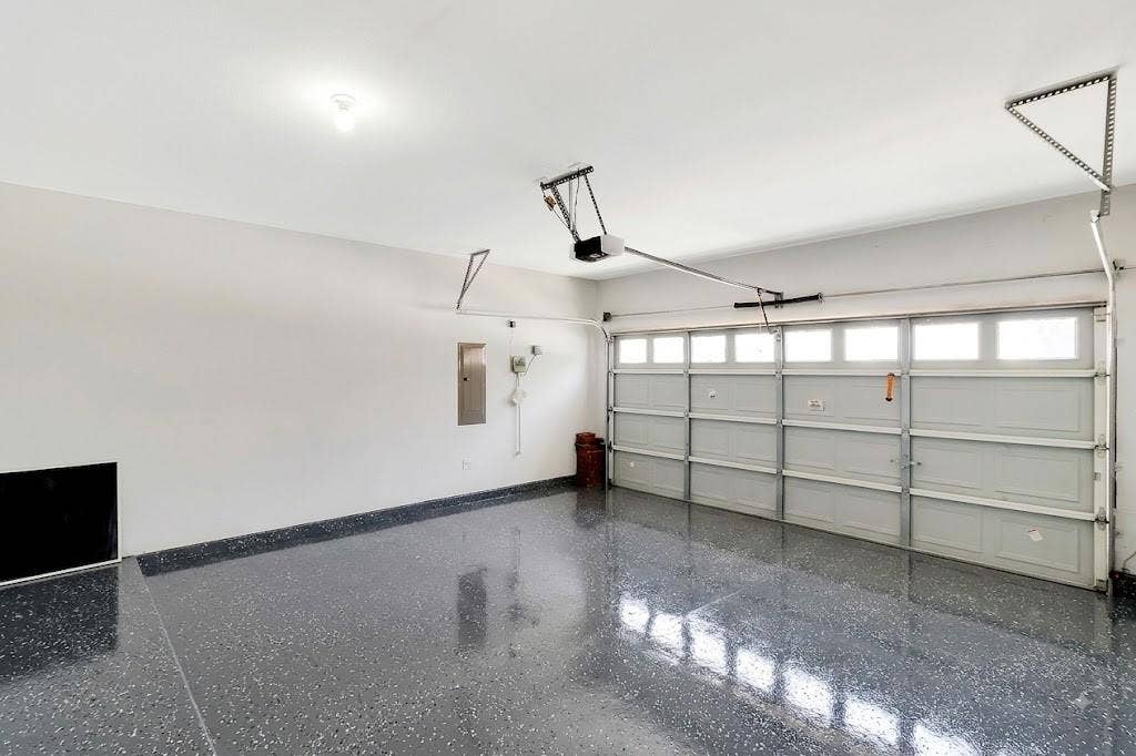 4908 Rushden Road, McKinney, TX 75070 Spacious garage featuring a durable epoxy floor, an automatic overhead door with integrated windows, and a ceiling-mounted light fixture