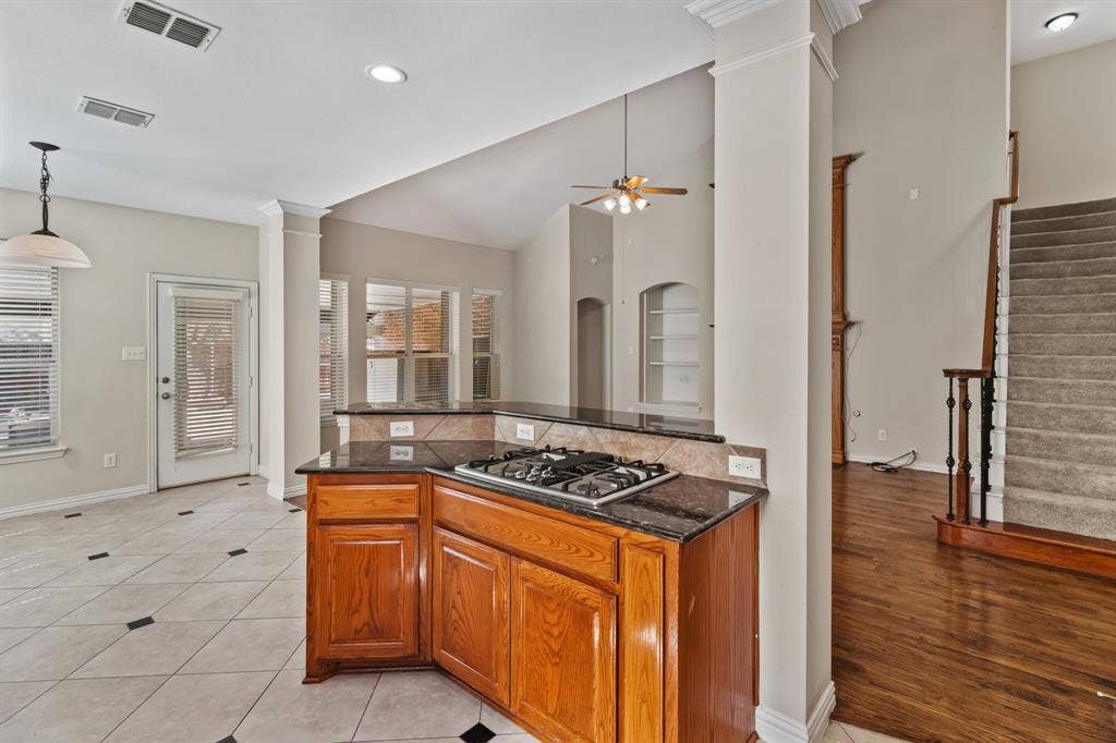 4908 Rushden Road, McKinney, TX 75070 Kitchen island with built-in gas cooktop, granite countertops, tile backsplash, and wood cabinetry
