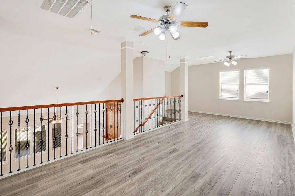 4908 Rushden Road, McKinney, TX 75070 Expansive open loft area featuring wood-finish flooring, two ceiling fans with lighting, and multiple windows