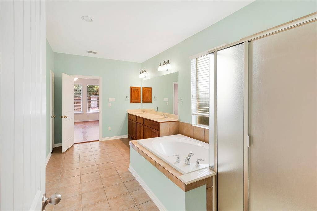 4908 Rushden Road, McKinney, TX 75070 Tiled flooring, dual vanity with wood-finish cabinetry and light-toned countertops, built-in bathtub, and a glass-enclosed shower