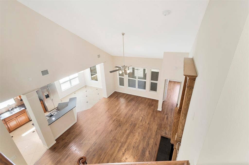 4908 Rushden Road, McKinney, TX 75070 Vaulted ceiling, wood-finish flooring, built-in kitchen island, multiple windows, and a ceiling fan with light fixture