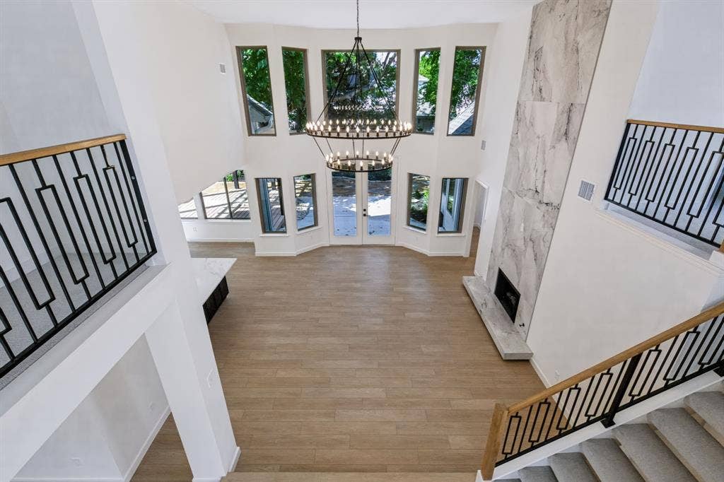6029 Buffridge Trail, Dallas, TX 75252 Vaulted ceilings, stunning fireplace and double chandelier lead seamlessly into the open kitchen on one side and first floor primary suite on the other