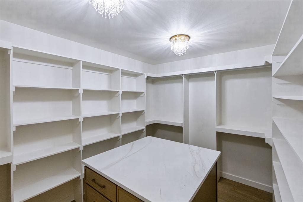 6029 Buffridge Trail, Dallas, TX 75252 Primary closet with 2 chandelier and custom island with drawers