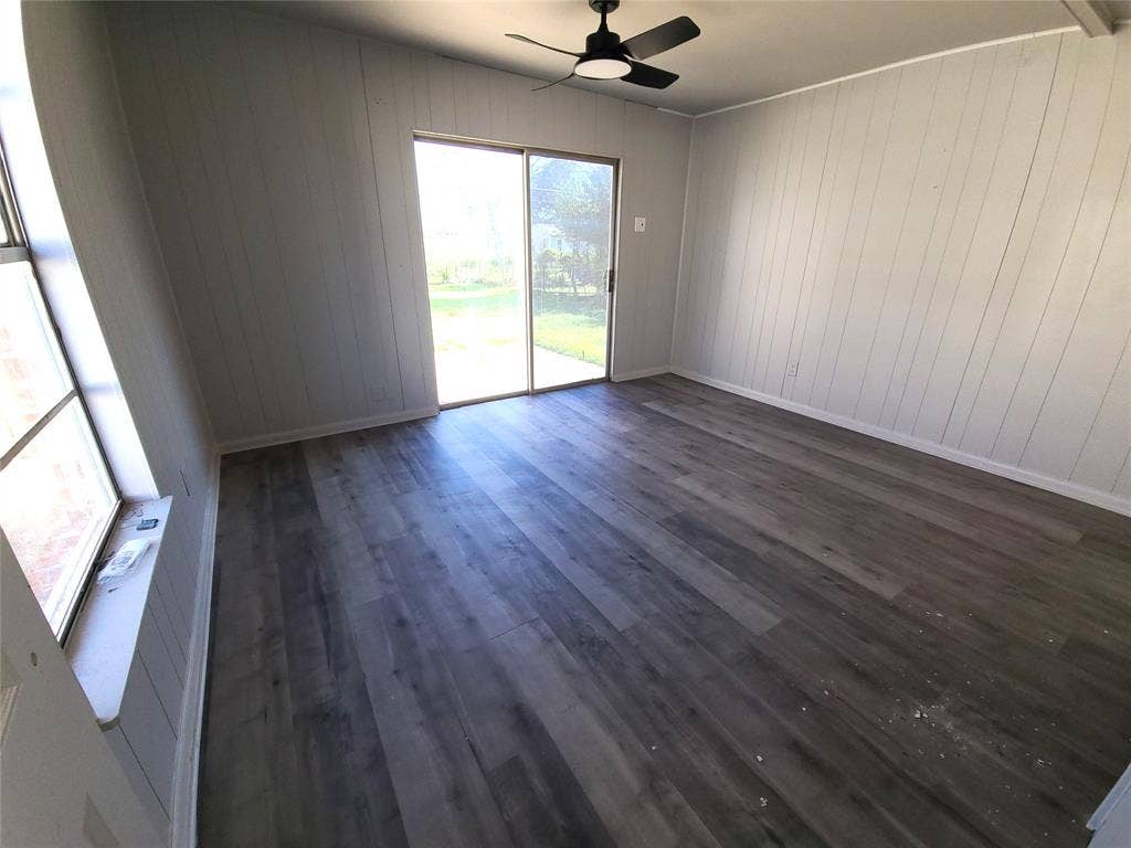 519 Dearborn Street, Waco, TX 76704 Primary Bedroom with dark wood finished floors, a ceiling fan, and wooden walls