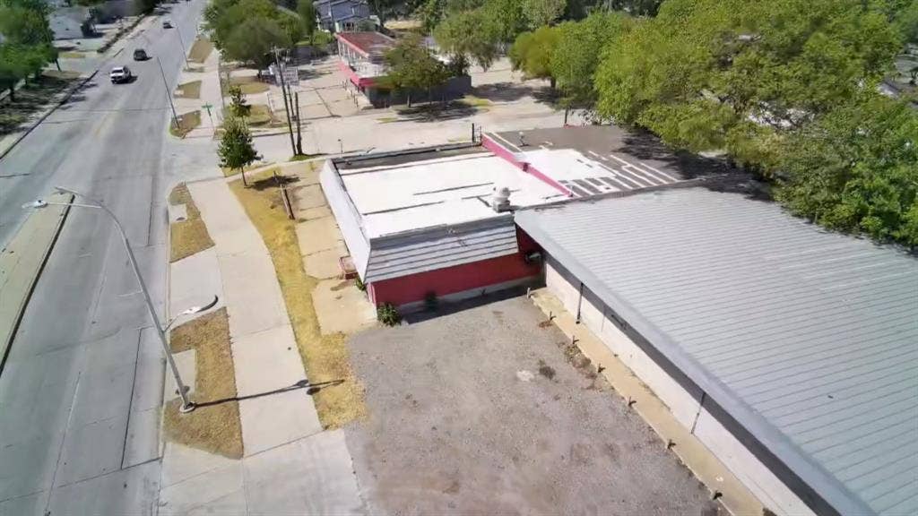 4606 Botham Jean Boulevard, Dallas, TX 75215 Commercial building with a flat roof, red siding, and an asphalt parking area