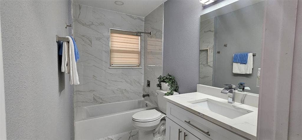 Full bathroom featuring a vanity with an integrated sink, polished chrome faucet, and a large mirror