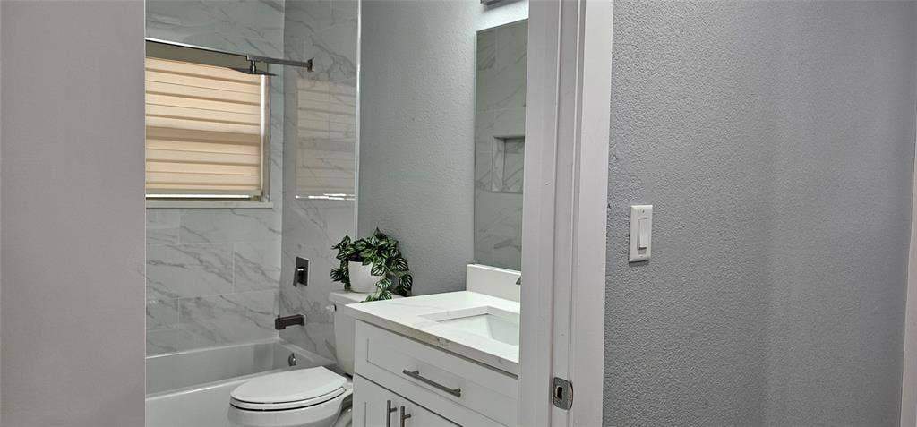 White vanity with an integrated sink and brushed nickel hardware, white stone-finish countertop, and wall-mounted mirror