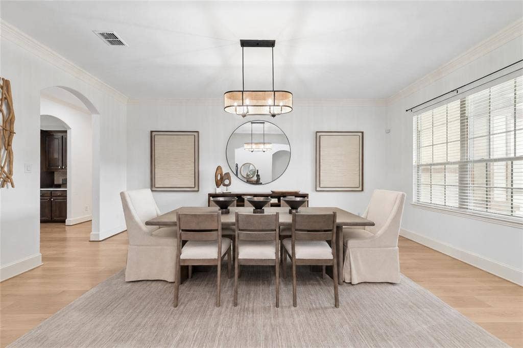 Expansive dining area featuring crown molding, wood-finish flooring, and a contemporary chandelier