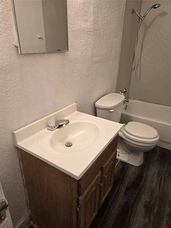 409 Monica Drive, Garland, TX 75041 Wood-finish flooring, vanity with integrated sink, chrome faucet, toilet, and bathtub with shower fixture