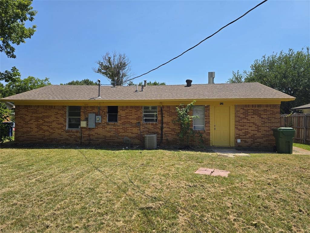 409 Monica Drive, Garland, TX 75041 Brick exterior with a brown shingle roof, yellow trim, and a yellow door
