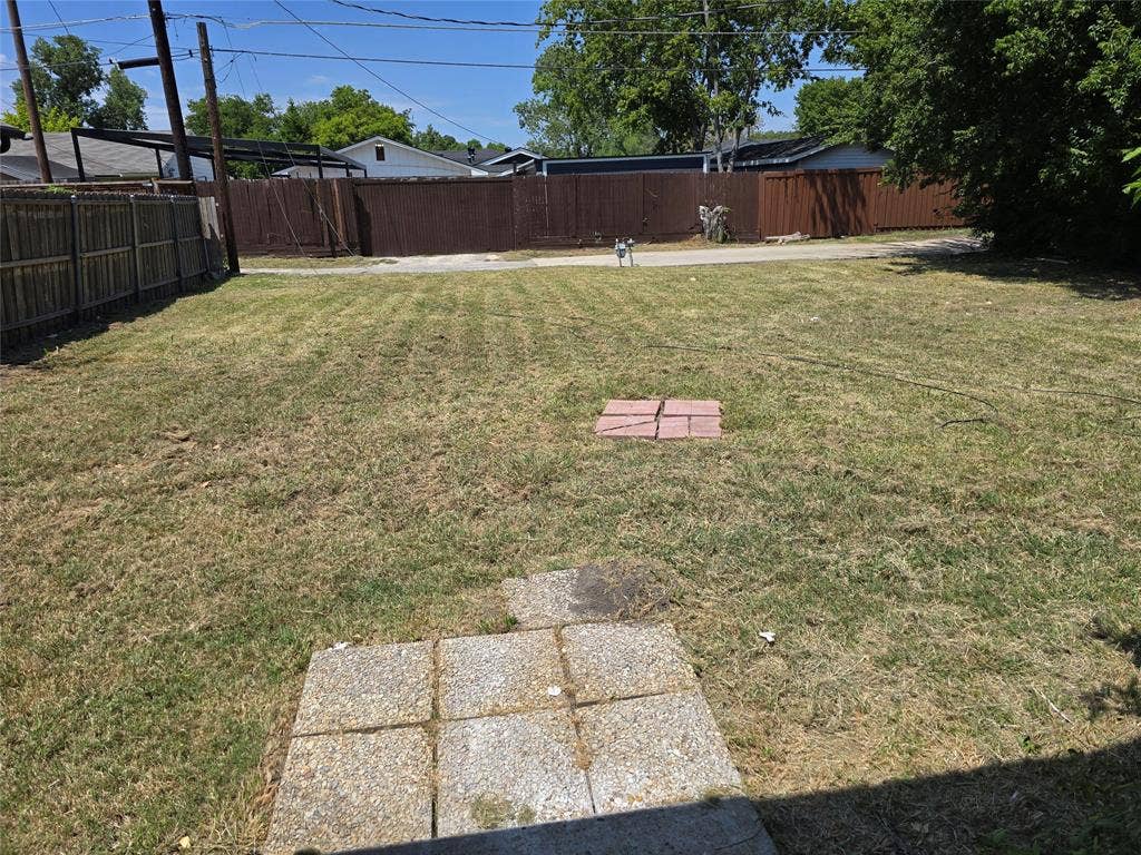 409 Monica Drive, Garland, TX 75041 Expansive backyard featuring a brown privacy fence, a wood-slat fence, and a concrete paver patio area