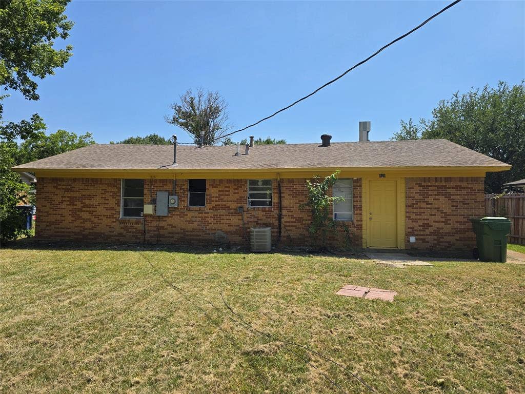 409 Monica Drive, Garland, TX 75041 Brick exterior with a yellow door and a shingled roof