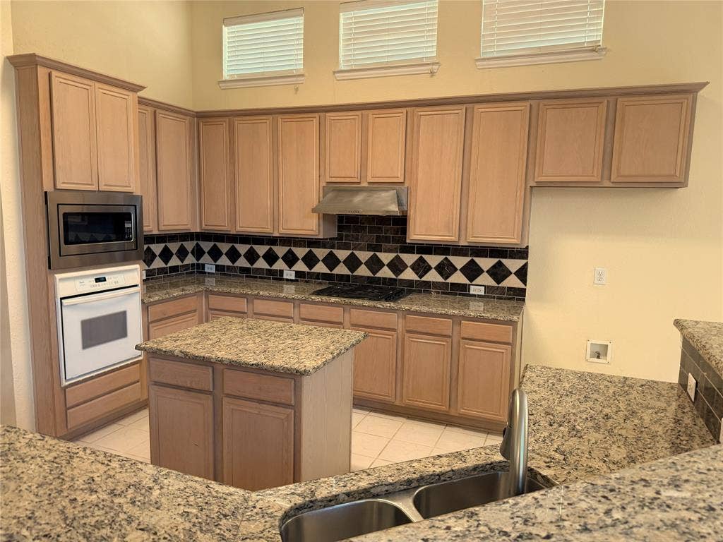 4413 Jenkins Drive, Plano, TX 75024 Kitchen featuring granite countertops, wood cabinetry, a built-in microwave, a gas cooktop, and a double basin stainless steel sink