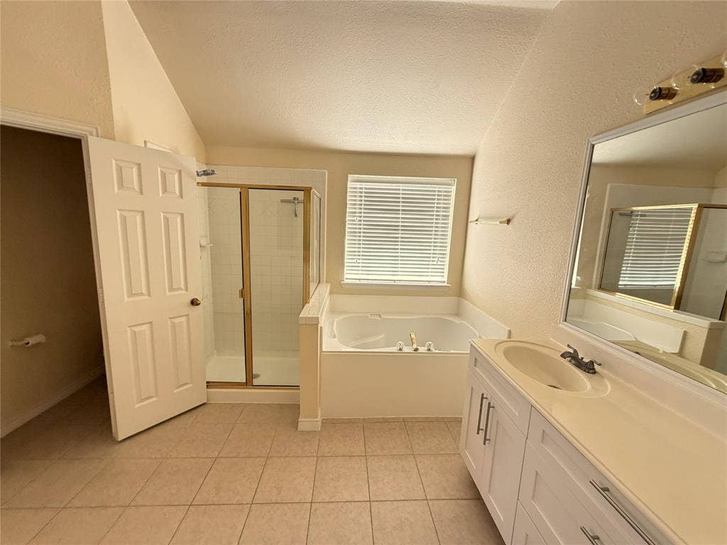 4413 Jenkins Drive, Plano, TX 75024 Tiled flooring, white vanity with dual sinks, white countertop, built-in bathtub, and enclosed shower with gold-toned trim