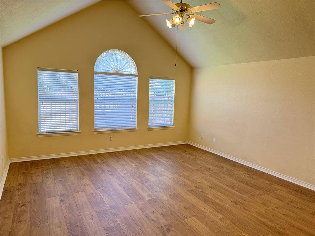 4413 Jenkins Drive, Plano, TX 75024 Vaulted ceiling with a ceiling fan light fixture, wood-finish flooring, and multiple windows including an arched window