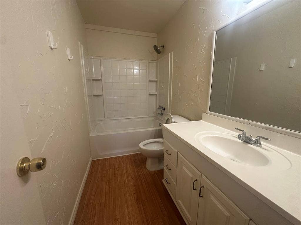 1408 15th Place, #2, Plano, TX 75074 Bathroom featuring a white vanity with integrated sink, wood-finish flooring, a full bathtub with a tiled shower surround, and a wall-mounted mirror