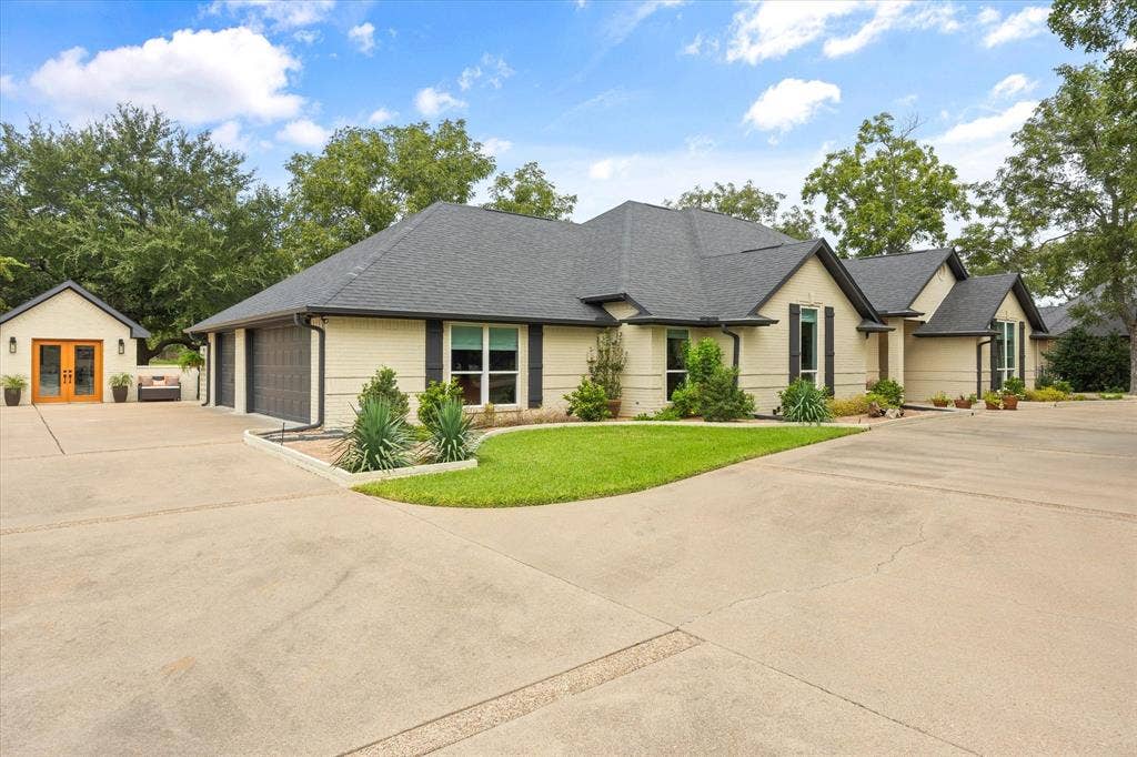 9604 Champions Drive, Granbury, TX 76049 Oversized Three Car Garage Featuring Work Bench and Cabinets, Epoxy Floor and Storage Closet. Detached Double Door Workshop with Epoxy Floor, Cabinets and Split HVAC Unit for Year-Round Enjoyment!