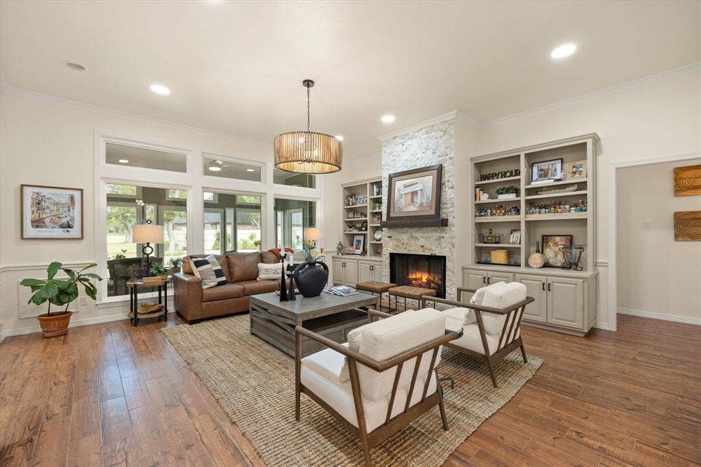 9604 Champions Drive, Granbury, TX 76049 A Great Great Room! Gas Fireplace Featuring Stacked Stone, Custom-Built Cabinets and Bookcases. Designer Light Fixture Completes this space,