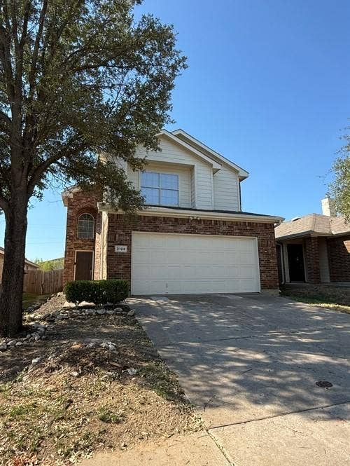 Two-story residence featuring a brick and siding exterior, an attached two-car garage, and a concrete driveway