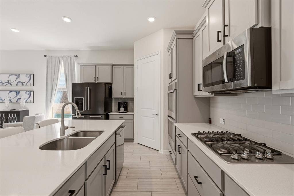 4808 Forest Crest Parkway, Arlington, TX 76005 Kitchen featuring light gray cabinetry, stainless steel appliances, a gas cooktop, a built-in microwave, and an island with an undermount sink