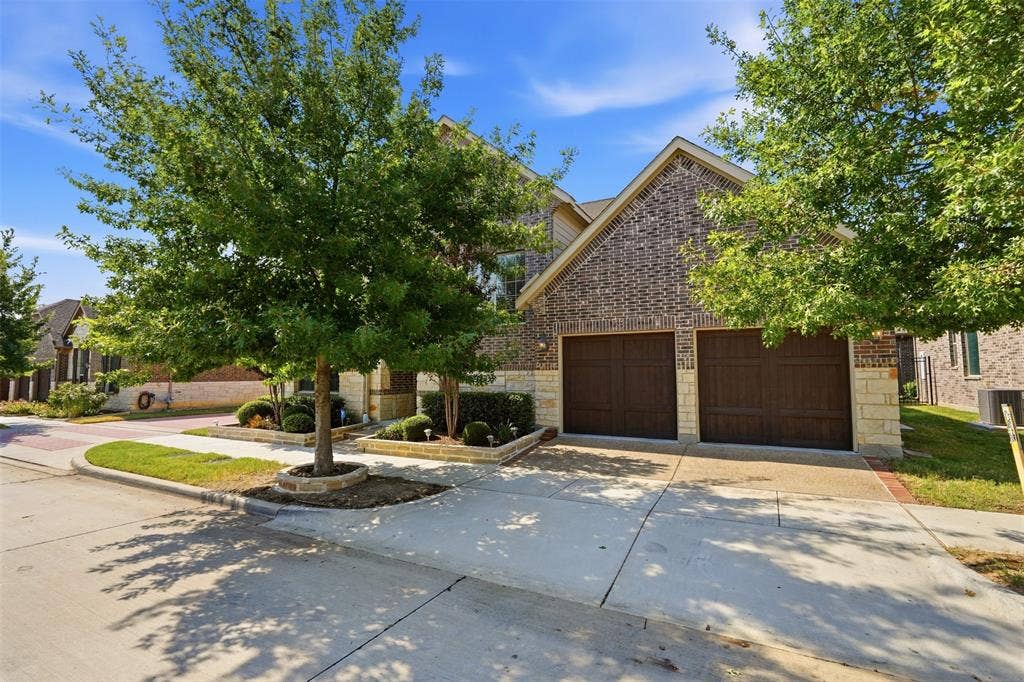 4808 Forest Crest Parkway, Arlington, TX 76005 Brick and stone exterior with a two-car garage featuring individual wood-panel doors
