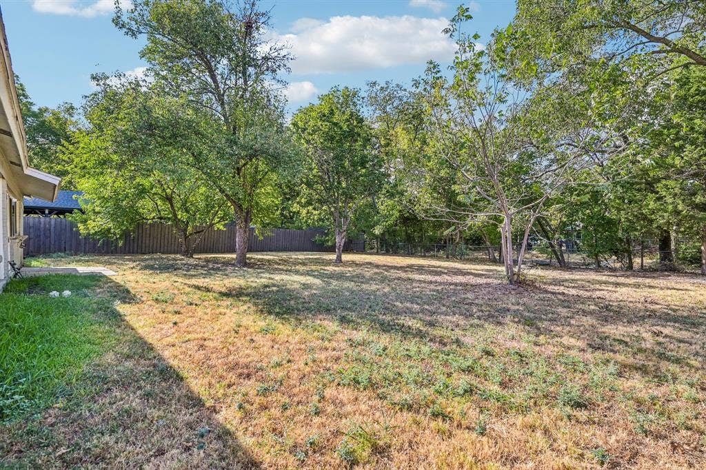 Expansive grassy area, mature trees, and privacy fencing