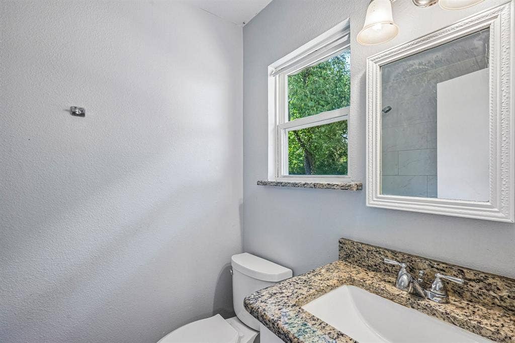Granite countertop with integral sink, chrome faucet, and decorative framed mirror