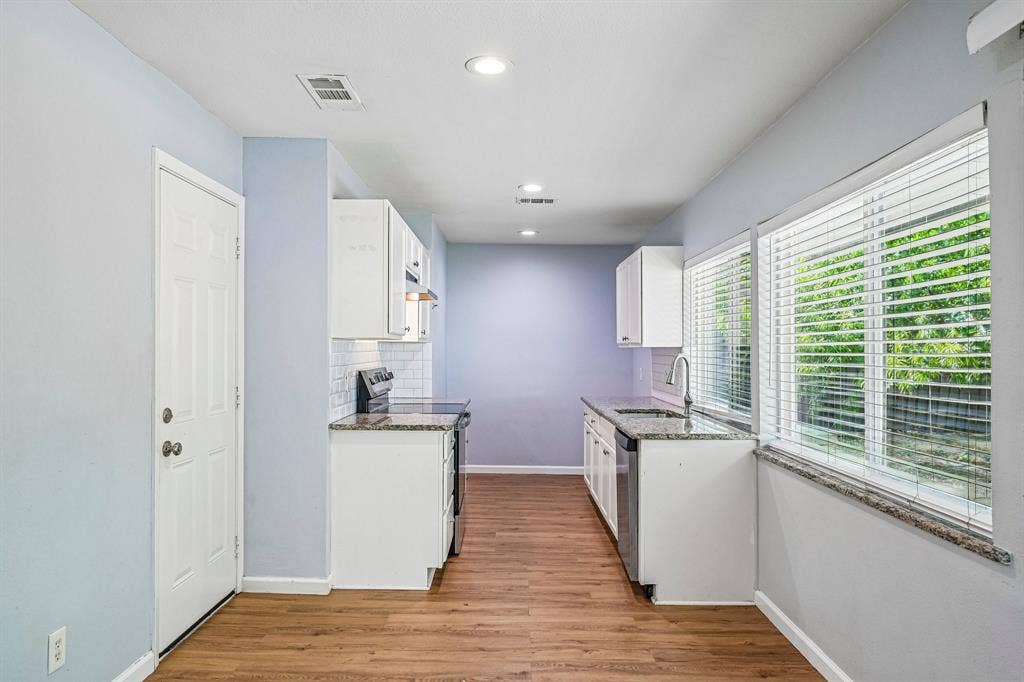 Contemporary kitchen featuring white cabinetry, granite countertops, subway tile backsplash, wood-finish flooring, and recessed lighting