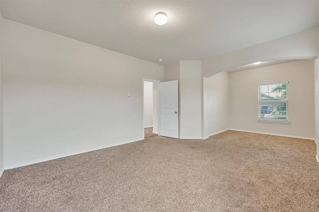 Carpeted room with neutral paint, a window with blinds, and an overhead light fixture