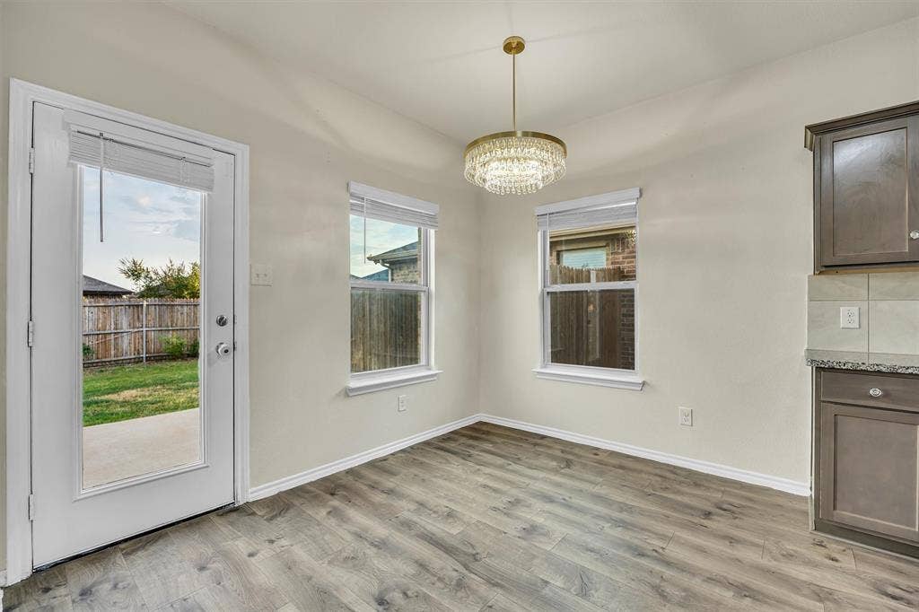 Wood-finish flooring, two large windows, and a glass-paneled exterior door